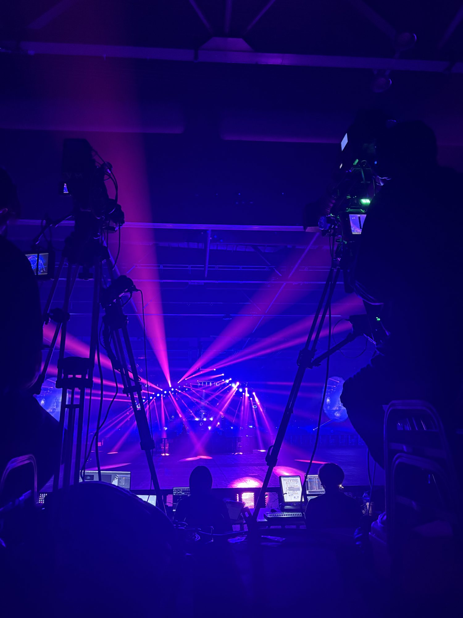 Cameras on tripods facing the stage at a concert at AsiaWorld-Expo