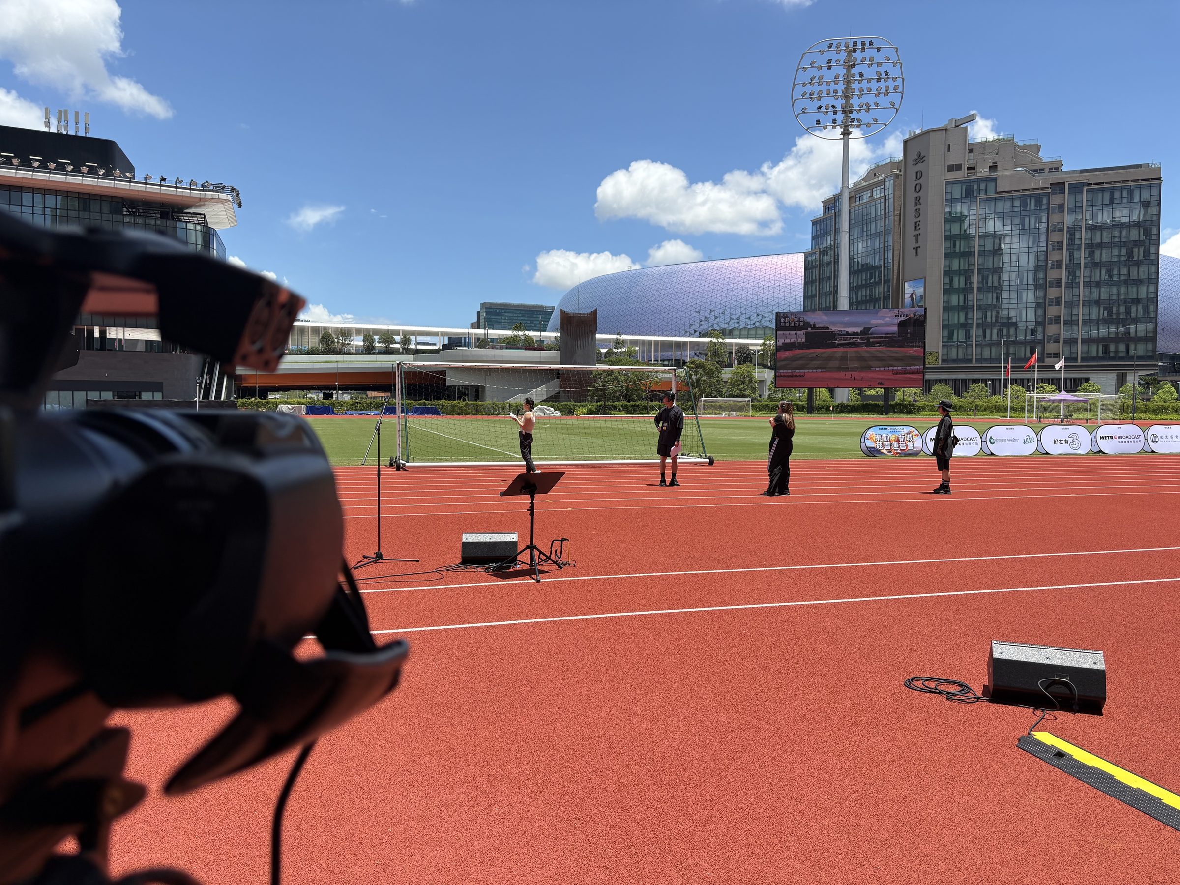 Pitch-side camera covering the track and performance setup at Kai Tak Youth Stadium